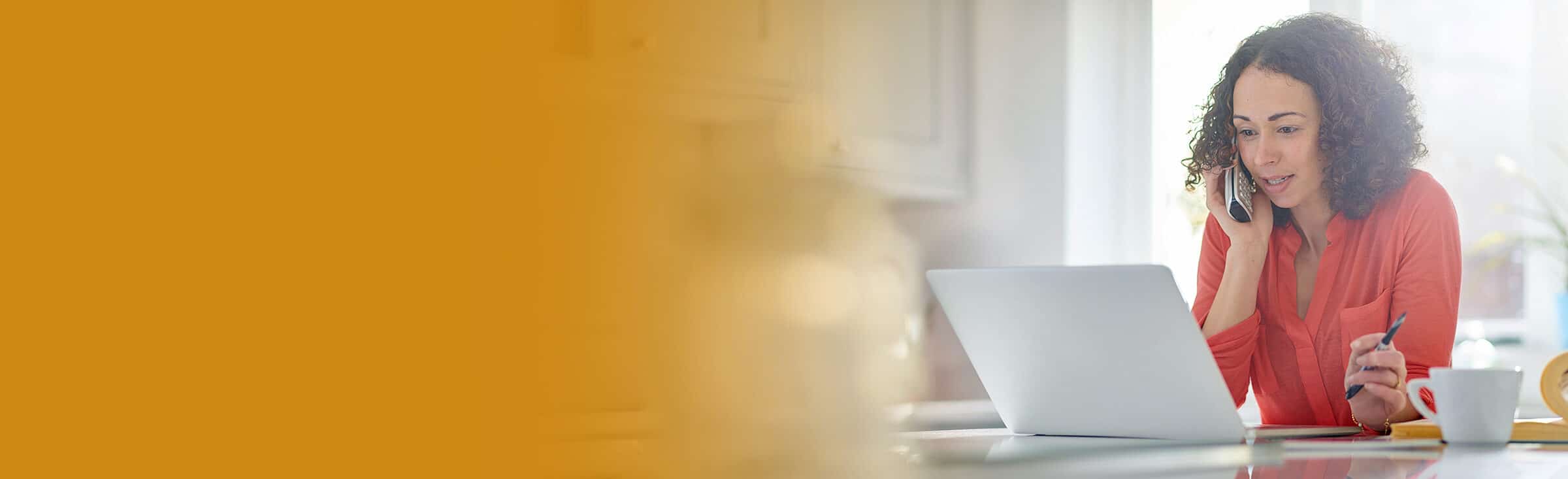 woman works on her computer while talking on the phone