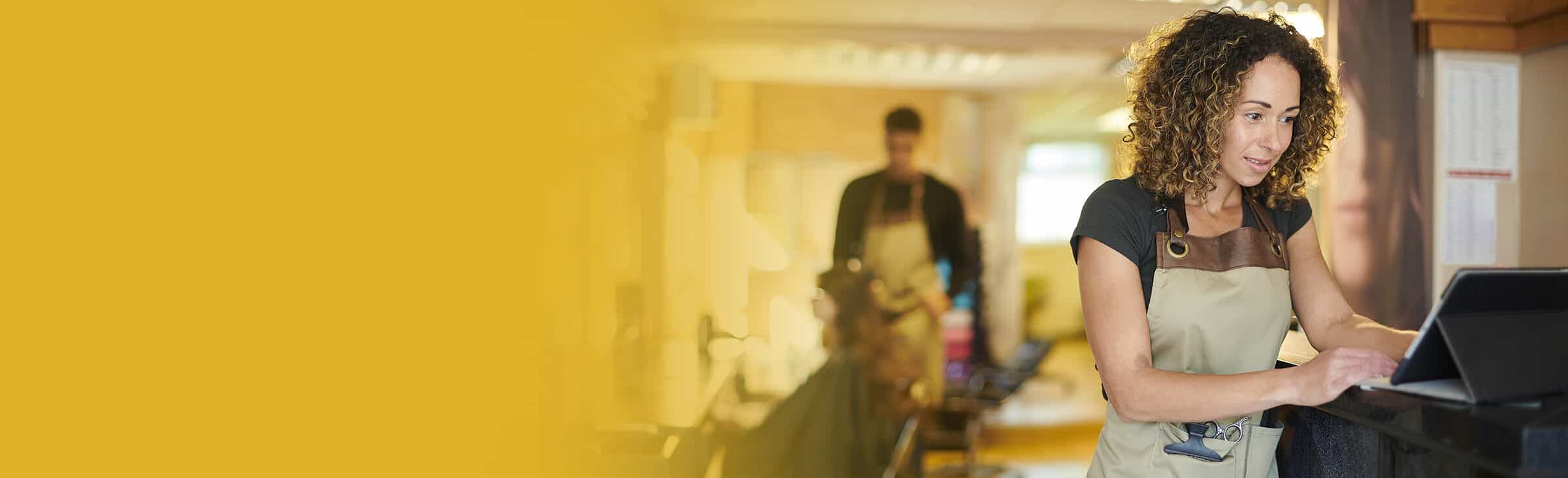 a woman working in a hair salon checks her tablet device