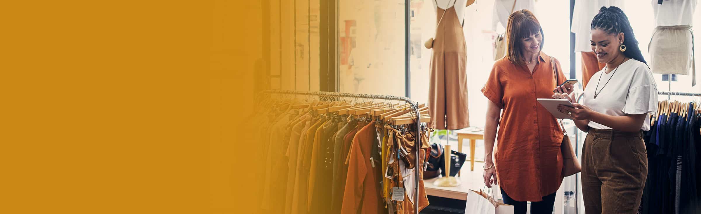 Two women look at a tablet in a clothing store
